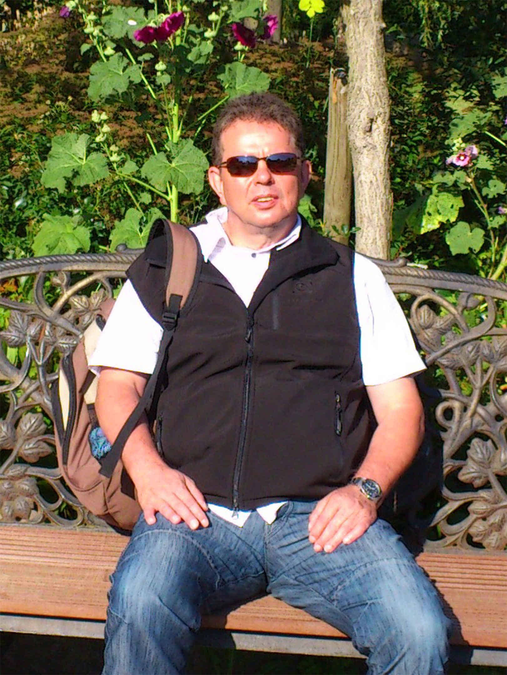 Foto: Joachim sitzt auf einer Parkbank in der Sonne.